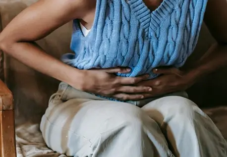 photo of woman holding stomach and bending over