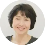 Portrait of an individual with short dark hair, smiling and wearing a dark top.